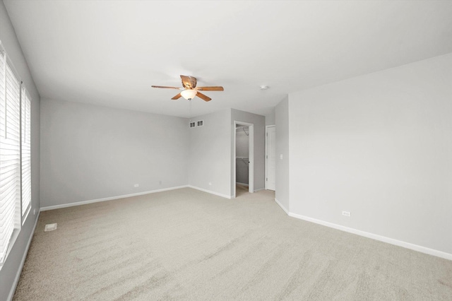 unfurnished room with a ceiling fan, light colored carpet, and baseboards