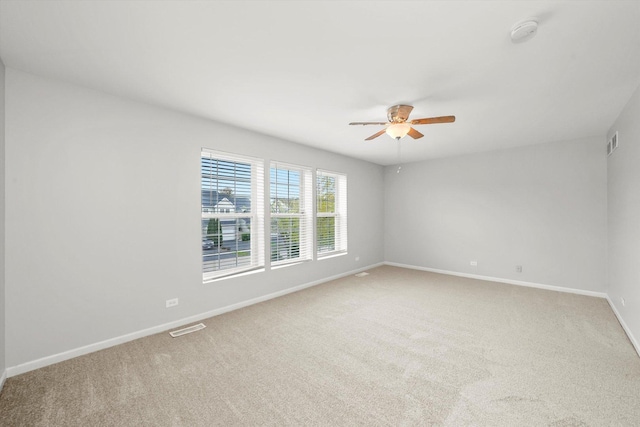 empty room with ceiling fan, baseboards, light colored carpet, and a smoke detector