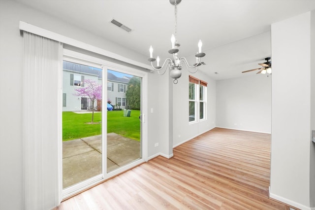 unfurnished dining area with a chandelier, wood finished floors, baseboards, and ceiling fan