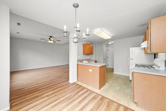 kitchen featuring a chandelier, light countertops, a sink, ceiling fan, and a peninsula