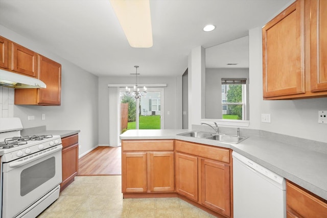 kitchen with white appliances, a sink, under cabinet range hood, light countertops, and a peninsula