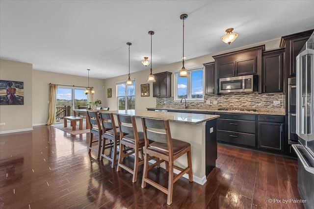 kitchen with a center island, appliances with stainless steel finishes, decorative backsplash, and dark wood-type flooring