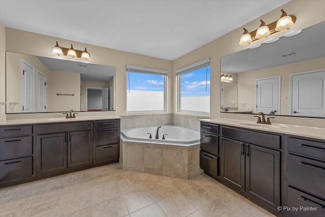 full bath featuring a sink, two vanities, a bath, and visible vents