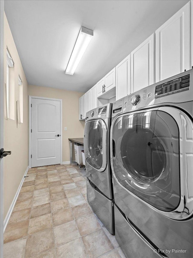 clothes washing area featuring cabinet space, baseboards, and washing machine and clothes dryer