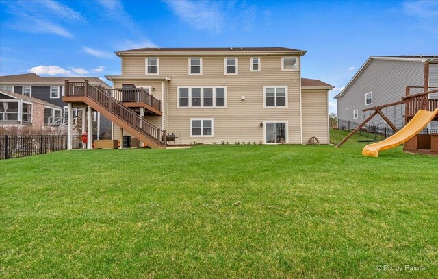 rear view of property featuring fence, a lawn, a playground, and stairway