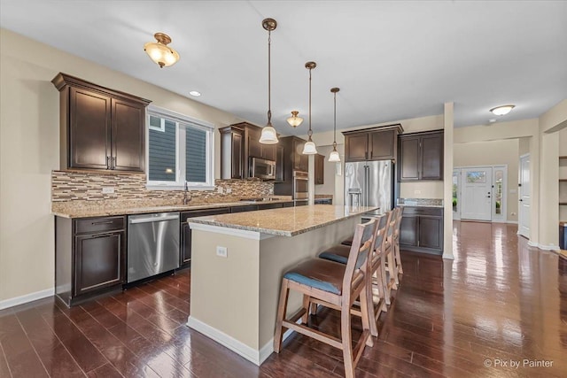 kitchen featuring dark brown cabinetry, appliances with stainless steel finishes, dark wood finished floors, and tasteful backsplash