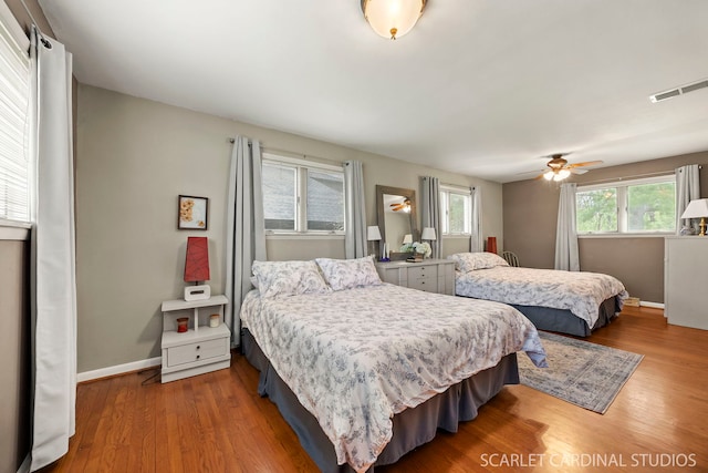 bedroom featuring a ceiling fan, baseboards, visible vents, and wood finished floors