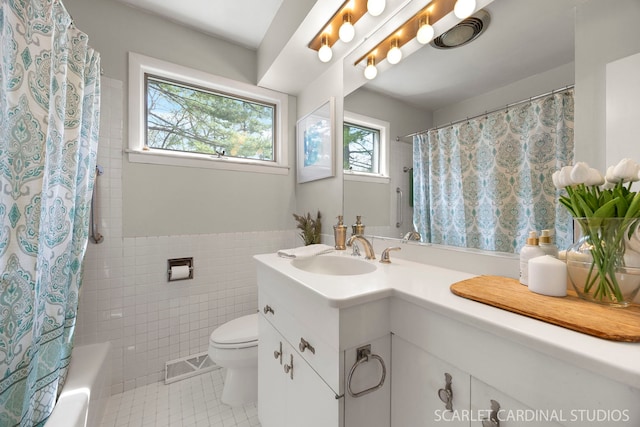 full bathroom featuring vanity, toilet, tile patterned floors, tile walls, and visible vents