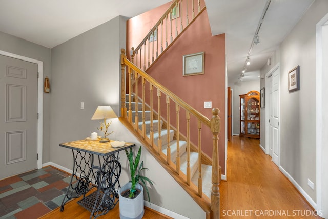 stairs with rail lighting, baseboards, and wood finished floors