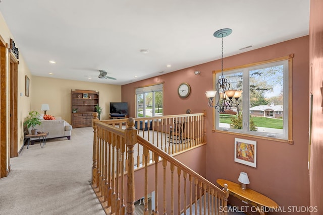 corridor featuring visible vents, light colored carpet, recessed lighting, a notable chandelier, and an upstairs landing
