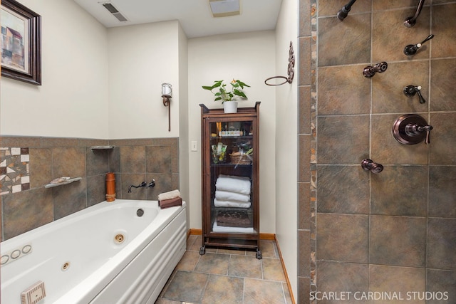 full bath with visible vents, baseboards, a tub with jets, stone finish floor, and a tile shower