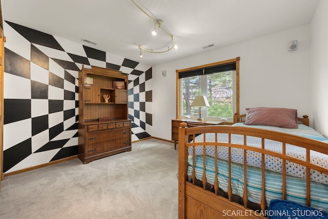 bedroom with an accent wall, light colored carpet, rail lighting, and visible vents