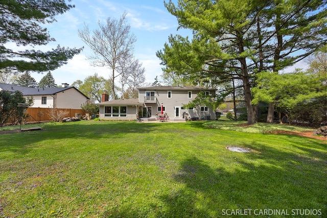rear view of house featuring a yard, a patio, fence, and a chimney