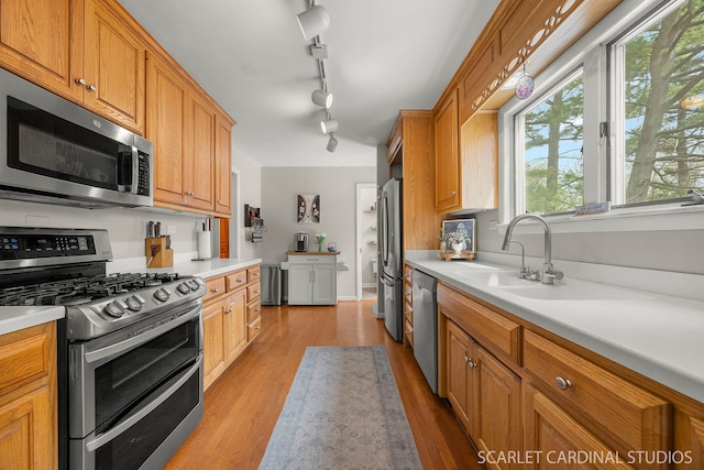 kitchen with light countertops, stainless steel appliances, a sink, and light wood-type flooring