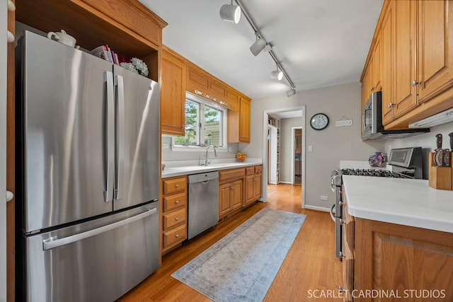 kitchen featuring light countertops, appliances with stainless steel finishes, a sink, and light wood-type flooring