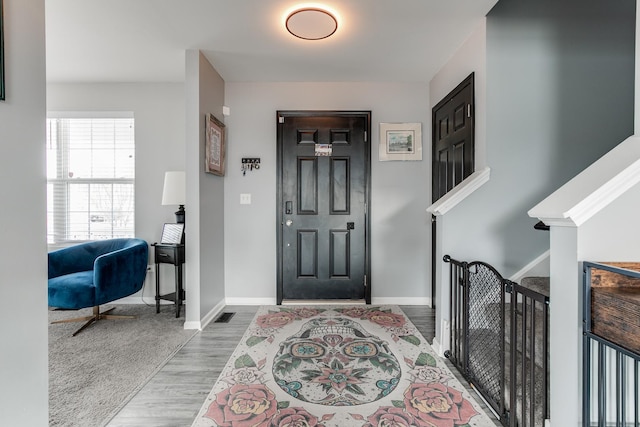 entryway with baseboards, visible vents, and wood finished floors