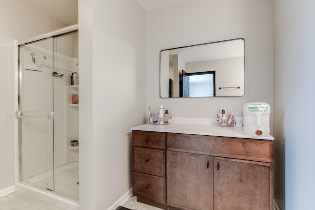 bathroom with baseboards, a shower stall, and vanity