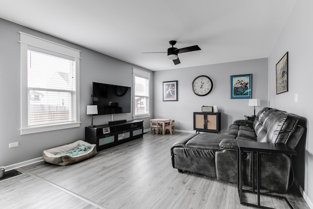 living room featuring baseboards, a ceiling fan, and wood finished floors