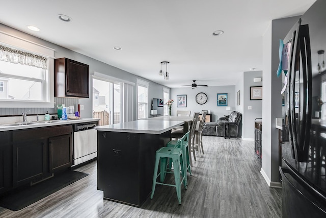 kitchen featuring freestanding refrigerator, stainless steel dishwasher, open floor plan, and light countertops