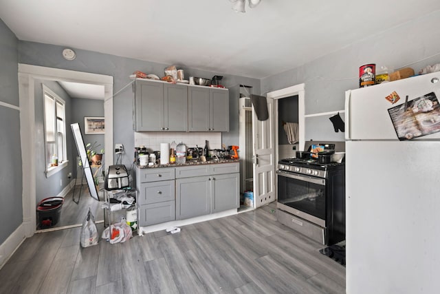 kitchen featuring wood finished floors, freestanding refrigerator, stainless steel range with gas cooktop, and gray cabinets