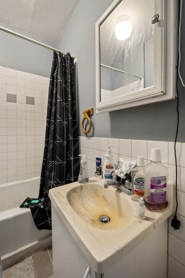 bathroom with shower / bath combo, tile walls, and vanity