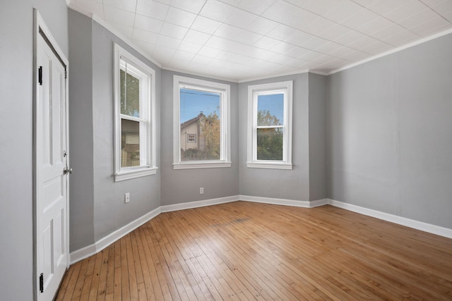 unfurnished room featuring crown molding, baseboards, and light wood finished floors