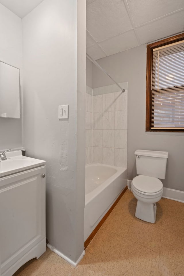 full bathroom featuring baseboards, toilet, vanity, tile patterned floors, and a drop ceiling