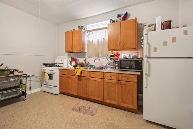 kitchen with white appliances, light countertops, backsplash, brown cabinetry, and a sink