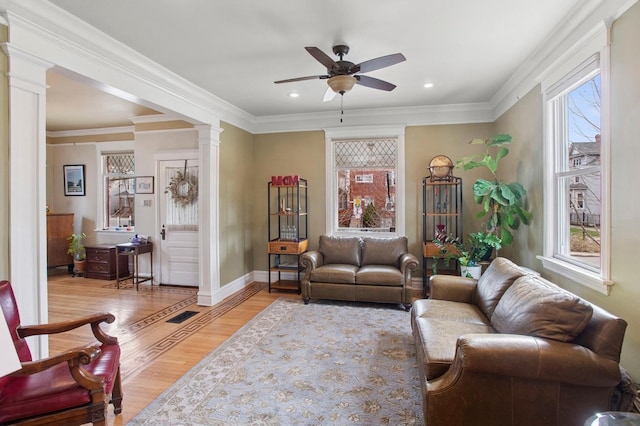 living room with crown molding, light wood-type flooring, decorative columns, and ceiling fan