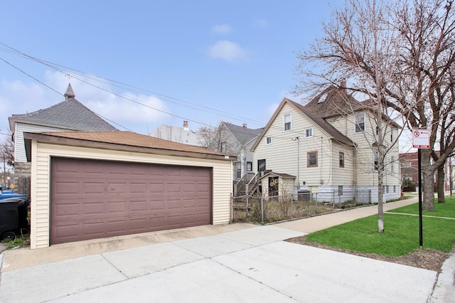 view of side of home with roof with shingles, an outdoor structure, fence, and a detached garage