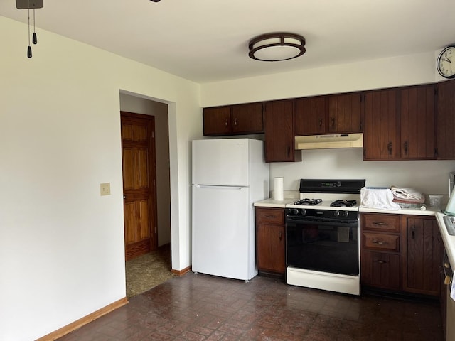 kitchen with under cabinet range hood, range with gas stovetop, light countertops, and freestanding refrigerator