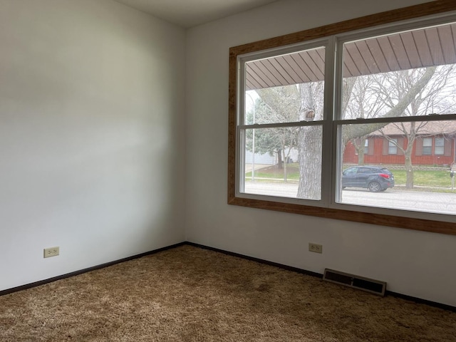 carpeted empty room featuring visible vents and baseboards