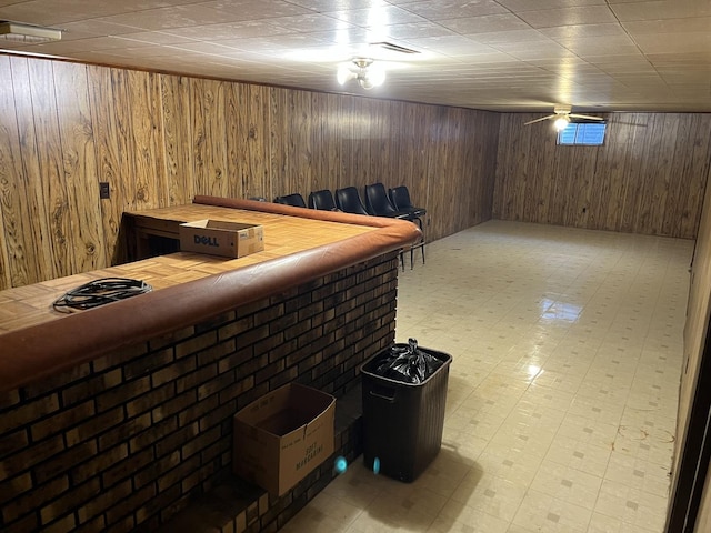 finished below grade area featuring wood walls, a bar, and light floors