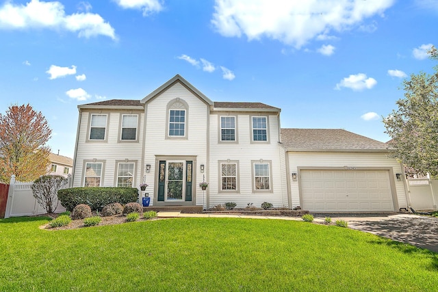 colonial house with a garage, fence, concrete driveway, and a front lawn
