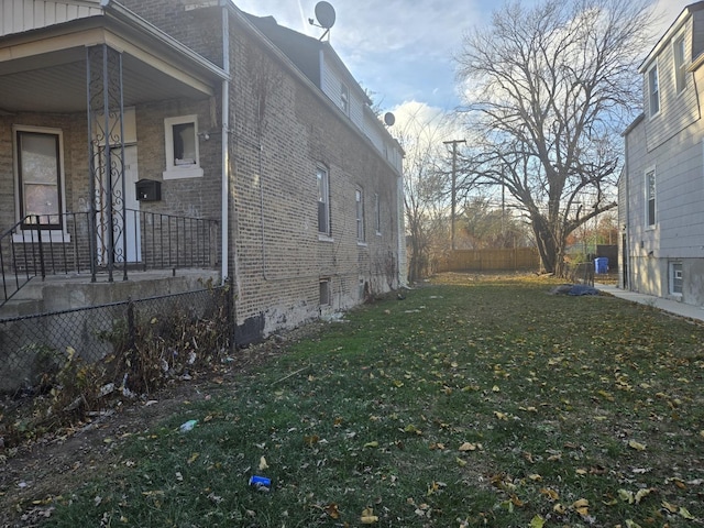 view of side of home featuring a yard, brick siding, and fence