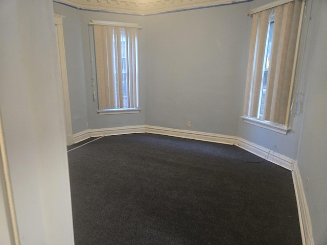 empty room featuring dark carpet, baseboards, and a healthy amount of sunlight