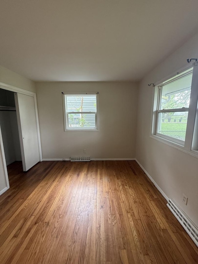 unfurnished bedroom featuring baseboards, a closet, wood finished floors, and visible vents