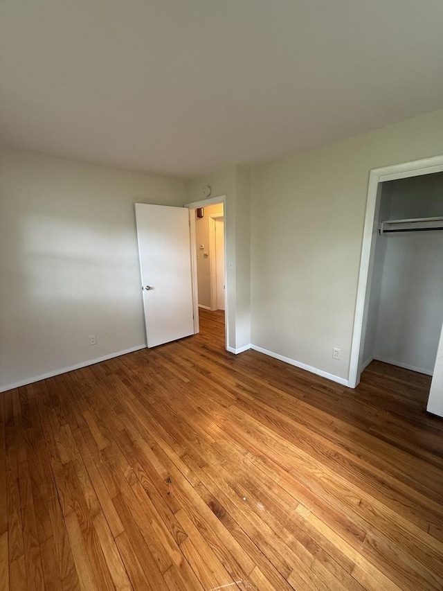 unfurnished bedroom featuring light wood-type flooring, baseboards, and a closet