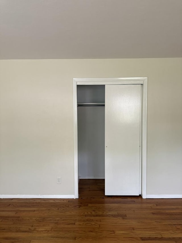 unfurnished bedroom featuring baseboards, a closet, and wood finished floors
