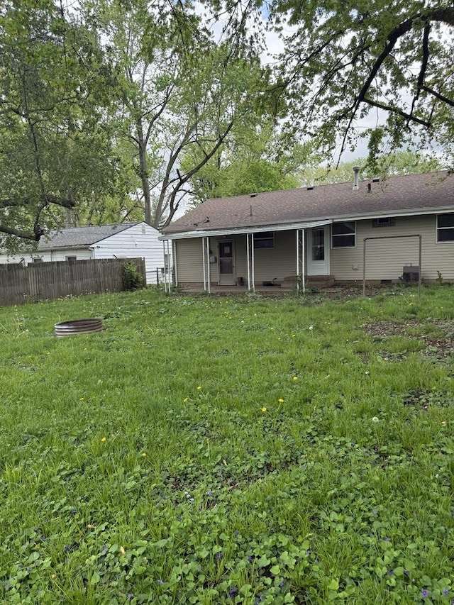 back of property with fence and a lawn
