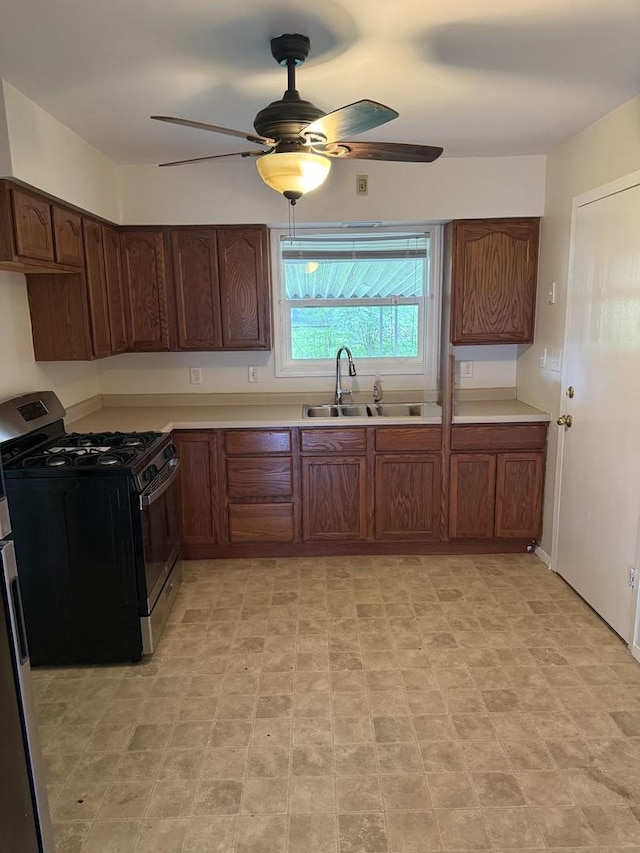 kitchen featuring light countertops, a ceiling fan, range with gas stovetop, and a sink