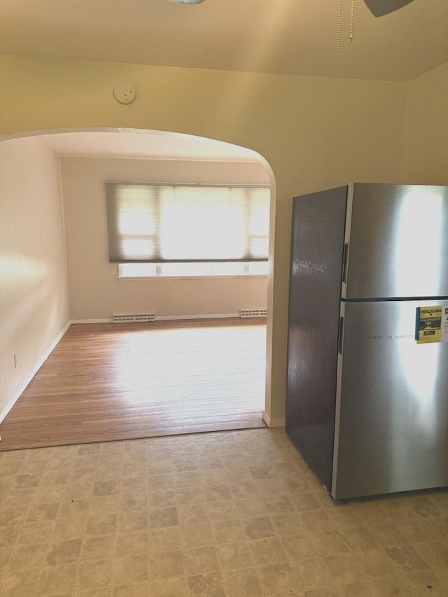 kitchen featuring baseboards, freestanding refrigerator, arched walkways, and visible vents