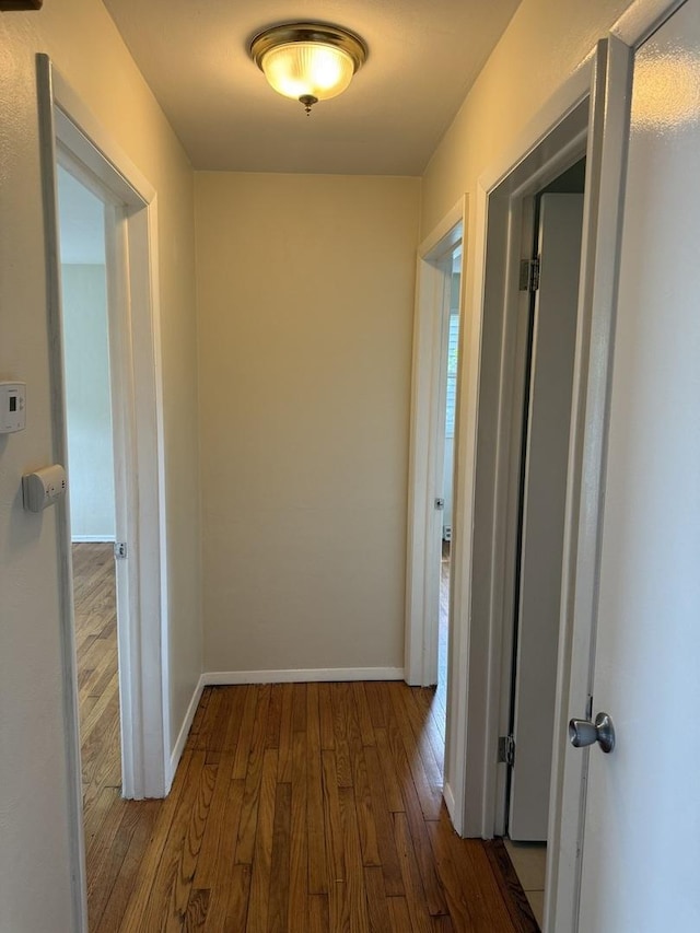 corridor featuring baseboards and wood finished floors