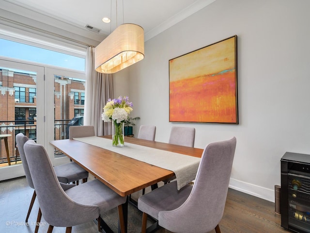 dining area with baseboards, wood finished floors, and crown molding