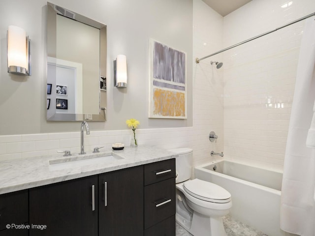 full bath with toilet, shower / tub combo, vanity, and tile walls