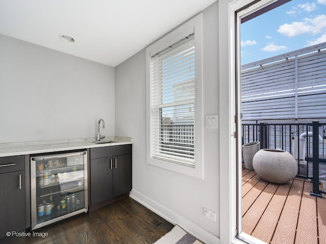 indoor wet bar featuring beverage cooler, dark wood-type flooring, and baseboards