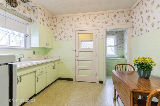 kitchen featuring wallpapered walls, green cabinetry, and wainscoting