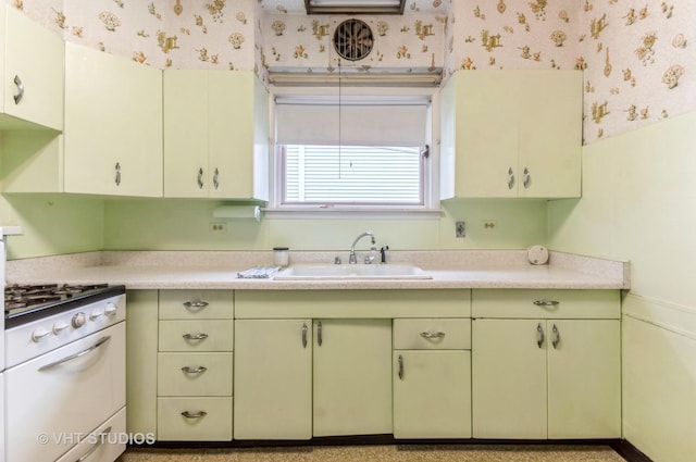 kitchen featuring a sink, wallpapered walls, green cabinets, white gas range oven, and light countertops