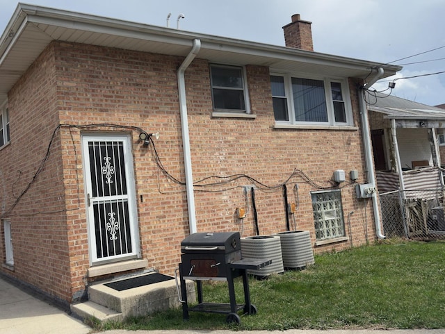 392 Luella Ave, Calumet City, IL 60409 - back of house featuring brick siding, cooling unit, a lawn, and a chimney