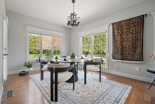 dining room featuring visible vents, baseboards, light wood-type flooring, and an inviting chandelier